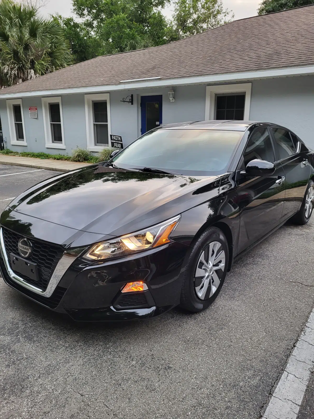 Glossy black sedan parked in front of a small shop building — Performance Mobile Detail in Ocala
