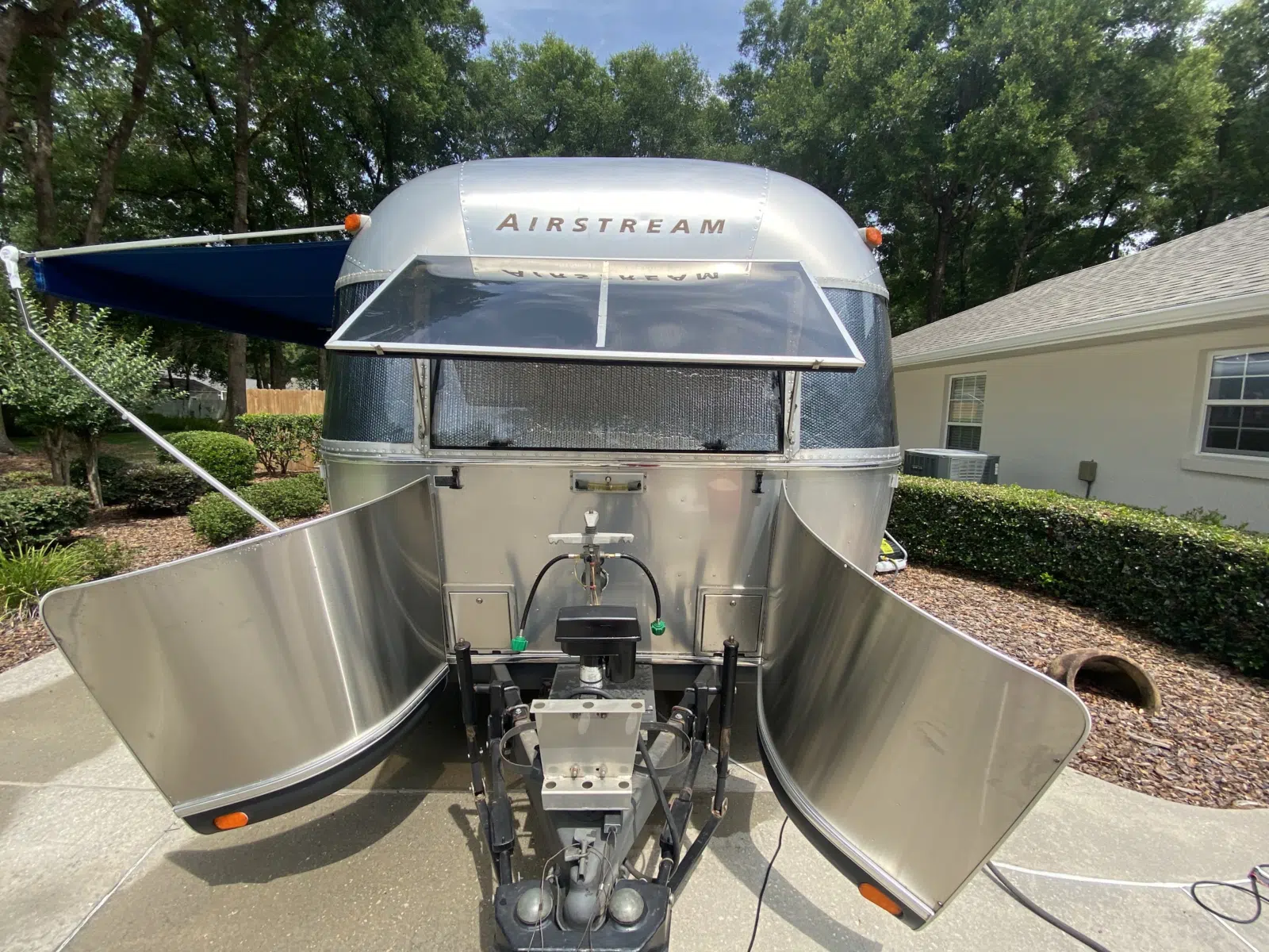 Polished Airstream trailer rear with hatches open in a driveway — Performance Mobile Detail in Ocala