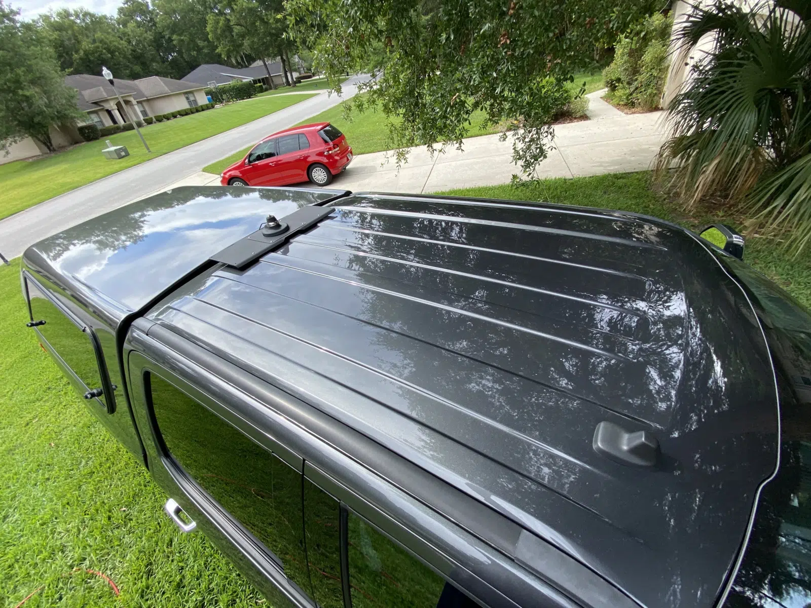 Glossy black truck bed cover reflected on a suburban lawn — Performance Mobile Detail in Ocala